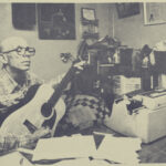 Johnny Mullins playing guitar and writing a song in his home study in Springfield, MO approx 1980